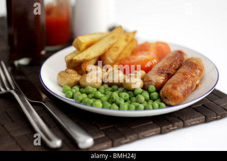 Frisch gekochte Mahlzeit von Wurst aus Schweinefleisch mit Chips Erbsen, Champignons und Tomaten auf einem Tisch mit Keine Personen Stockfoto