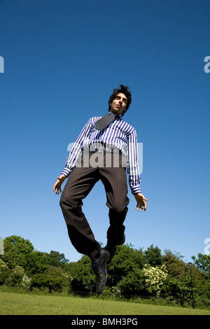 Mann im Hemd, Krawatte und Hose springen im park Stockfoto