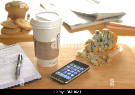 eine Take-away Tasse Kaffee auf dem Schreibtisch mit einem iphone Stockfoto
