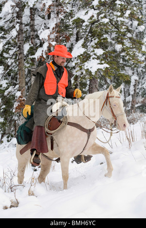 Cowboy Jäger weiß Reitpferd im Schnee jagen Stockfoto