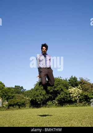 Mann im Hemd, Krawatte und Hose springen im park Stockfoto