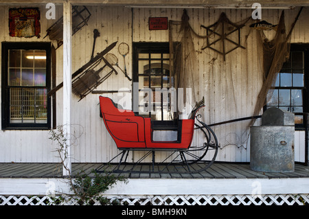 Roter Schlitten auf der Veranda an der Diebe Markt Antiquitätenladen in Mount Pleasant, South Carolina Stockfoto