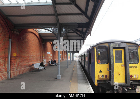 eine traditionelle Bahnhof mit dem Zug in einer Hertfordshire Stadt mit einem Mann zu Fuß einen Zug zu erhalten Stockfoto