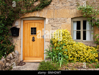 Hölzerne Eingangstür und Fenster auf einem typischen Cotswold Steinhaus in England, UK Stockfoto