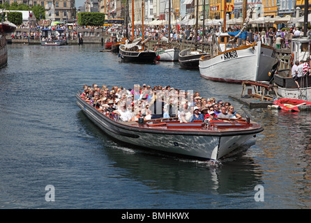 Ein Kanal Tour Kreuzfahrt Schiff voller Sommertouristen verlassen Nyhavn auf eine Rundfahrt im Hafen von Kopenhagen Stockfoto