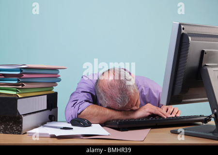 Überarbeiteten Mann an seinem Schreibtisch schlafen Stockfoto