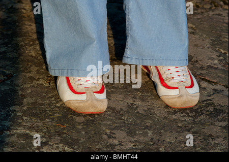 Weiße und rote Turnschuhe unter ein paar blaue Hosen Stockfoto