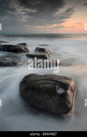 Eine Flut spült inmitten der Felsen im Dunraven Bay in der Nähe von Southerndown, Wales Stockfoto