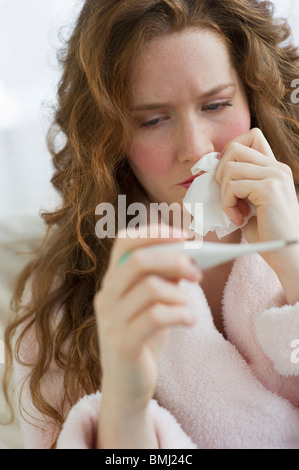 Kranke Frau betrachten thermometer Stockfoto