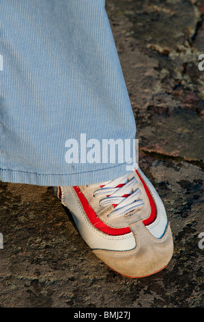 Weiße und rote Turnschuhe unter ein paar blaue Hosen Stockfoto