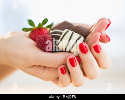 Hand mit Schokolade, Himbeere und Erdbeere Stockfoto