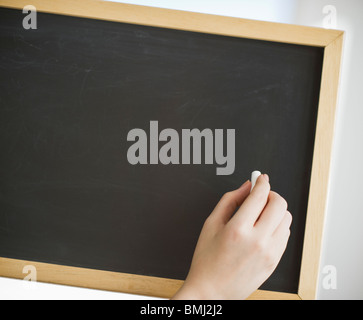Hand mit Kreide vor leeren Tafel Stockfoto