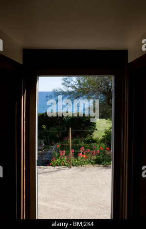 Blick durch eine Tür zu einem Garten mit dem Meer hinaus. Stockfoto