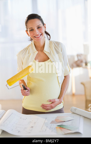 Schwangere Frau mit einem Farbroller Stockfoto