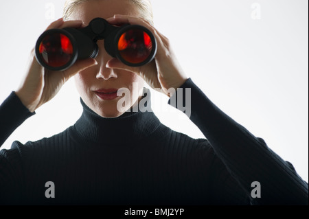 Frau, die durch ein Fernglas Stockfoto