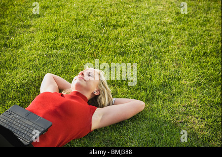 Frau liegt auf dem Rasen mit laptop Stockfoto