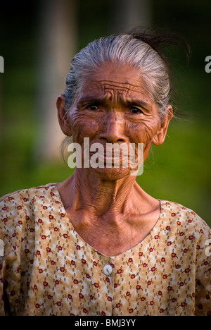 Eine ältere balinesische Frau, wer die harte Arbeit auf ihrem Gesicht zeigt, gesehen in den Reisfeldern der Sideman, Bali, Indonesien. Stockfoto