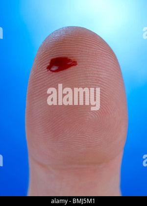 Makro-Ansicht eines Tropfens echtes Blut auf eine menschliche Daumen. Stockfoto