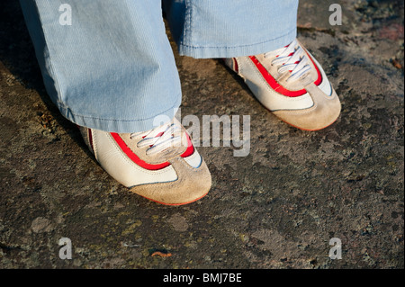 Weiße und rote Turnschuhe unter ein paar blaue Hosen Stockfoto