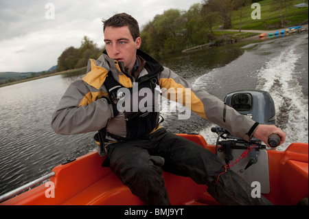 ein junger Mann Betrieb eine kleine Außenbordmotor Boot auf Bala Lake, North Wales UK Stockfoto