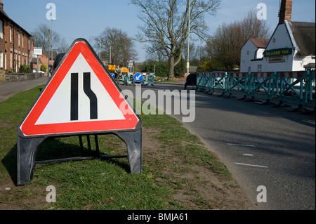 Straßenschild und Hindernisse auf einer englischen Straße bei Reparaturarbeiten. Stockfoto