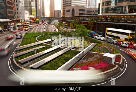 Die Innenstadt von Central Hong Kong an Hauptverkehrszeit Verkehr mit schnell fließenden Verkehrs, Autos Bewegung verwischt an einem Kreisverkehr erfasst. Stockfoto