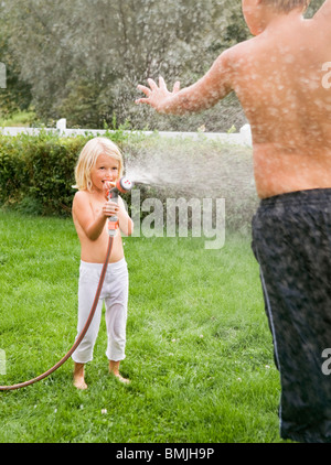 Mädchen spritzen Wasser auf jungen Stockfoto