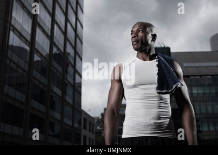 Passen Sie Mann trägt Sportbekleidung hintergründig durch moderne Stadtgebäude