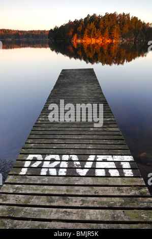 Pier am See mit Bäumen, die im Wasser reflektiert Stockfoto