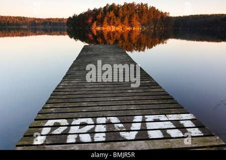 Pier am See mit Bäumen, die im Wasser reflektiert Stockfoto