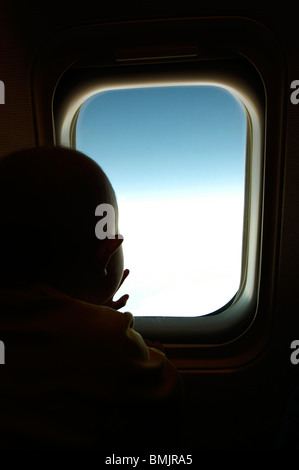 Ein Baby aus einem Fenster in einer Ebene Stockfoto