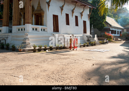 Buddhistische Mönche spazieren Sie durch das Gelände ihres Tempels in Luang Prabang Laos Stockfoto