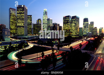 Die Skyline von Downtown Los Angeles, Kalifornien, USA, leuchtet in der Dämmerung mit Lichtern von Bürogebäuden und Autobahnverkehr. Stockfoto