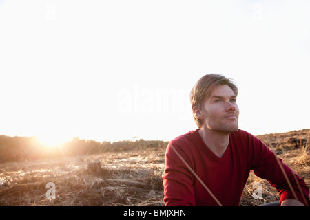 Mann sitzt im Freiland während des Sonnenuntergangs Stockfoto