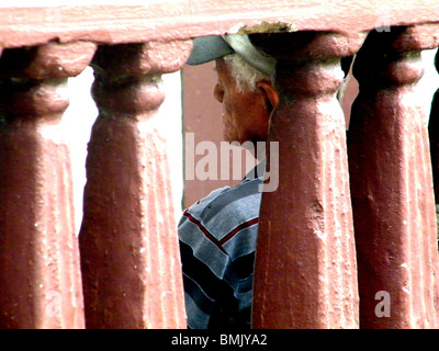 Ein älterer Obdachloser Mann sitzt eine rissige Wand in Puerto Plata, Dominikanische Republik Stockfoto