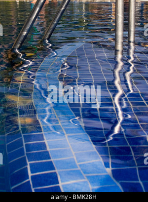 Spiegelungen im Wasser und eine Leiter durch eine am Pool Stockfoto