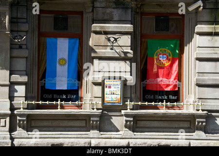 Die alte Bank Bar mit zwei internationalen Fahnen drapiert über die Fenster Werbung ihre live TV zeigt von der WM 2010 Stockfoto