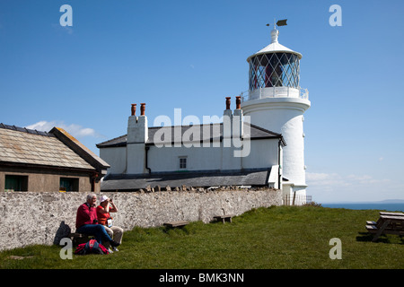 Menschen sitzen auf der Bank am Leuchtturm Caldey Island Wales UK Stockfoto