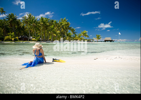 Ein Mann und eine Frau an einem Strand eine tahitian Hotelanlage mit Schnorchelausrüstung (Flossen und Maske). Sie sind auf Sand Sonnenbaden. Stockfoto