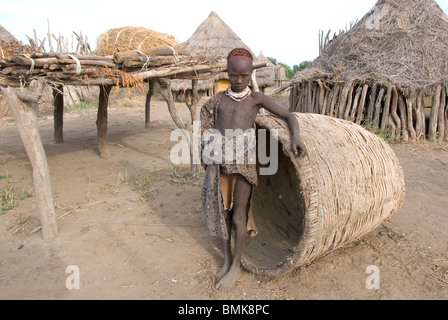 Äthiopien: Unteren Omo River Basin, Karo Dorf von Duss, Mädchen mit geflochtenen Korb vor der traditionellen Häuser steht Stockfoto