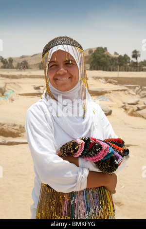 Eine nubische afrikanische Teenagerin im Alter von 14 Jahren in traditionellen Kostümen, die Perlenarbeiten in Gizeh, Kairo, Ägypten, Nordafrika verkauft Stockfoto