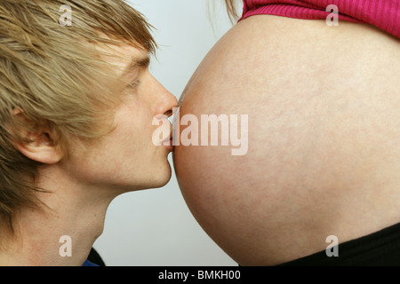 Junger Mann küssen seine schwangere Frau Beule Stockfoto