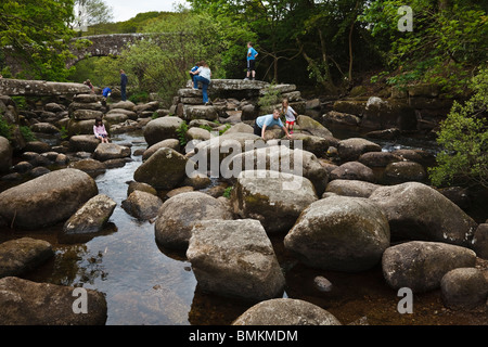 Kinder klettern über Felsblöcke in East Dart River an der Dartmeet. Stockfoto