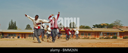 Nigeria, Jos, Schüler und Schülerinnen in ihren lila und blau Schuluniform laufen insgesamt auf einem Feld. Stockfoto