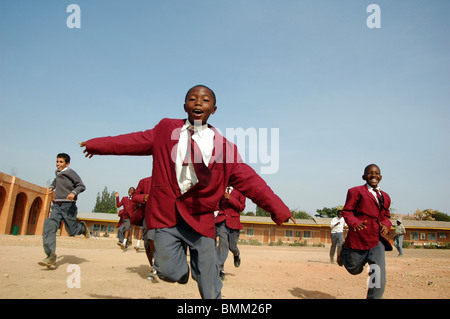 Nigeria, Jos, Schüler und Schülerinnen in ihren lila und blau Schuluniform laufen insgesamt auf einem Feld. Stockfoto