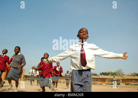 Nigeria, Jos, Schüler und Schülerinnen in ihren lila und blau Schuluniform laufen insgesamt auf einem Feld. Stockfoto