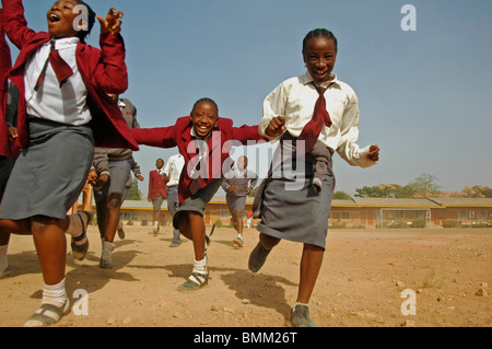 Nigeria, Jos, Schüler und Schülerinnen in ihren lila und blau Schuluniform laufen insgesamt auf einem Feld. Stockfoto