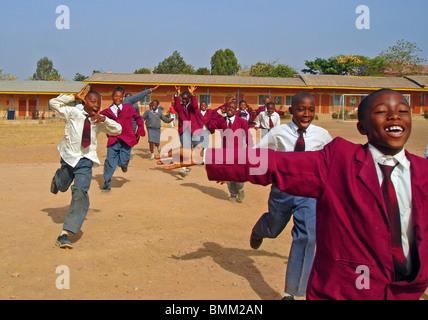 Nigeria, Jos, Schüler und Schülerinnen in ihren lila und blau Schuluniform laufen insgesamt auf einem sandigen Feld. Stockfoto