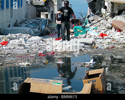 Ein Mann spiegelt sich in einer Pfütze, während er durch zentrale Port au Prince nach dem Erdbeben in Haiti geht Stockfoto