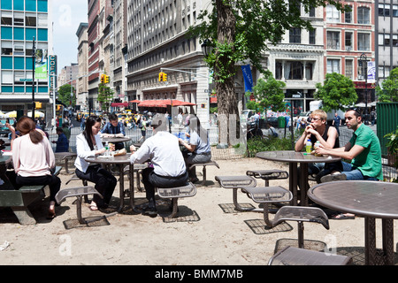 Büroangestellte & andere genießen Mittagessen im Freien bei Sonnenschein an Tischen zur Verfügung gestellt in Union Square Manhattan New York City Stockfoto